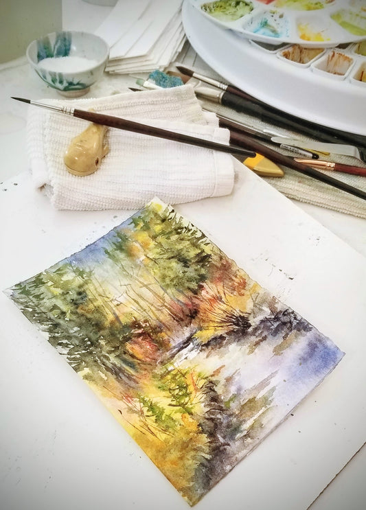 Watercolor painting of a mountain stream in progress; snapshot of the art studio workspace.