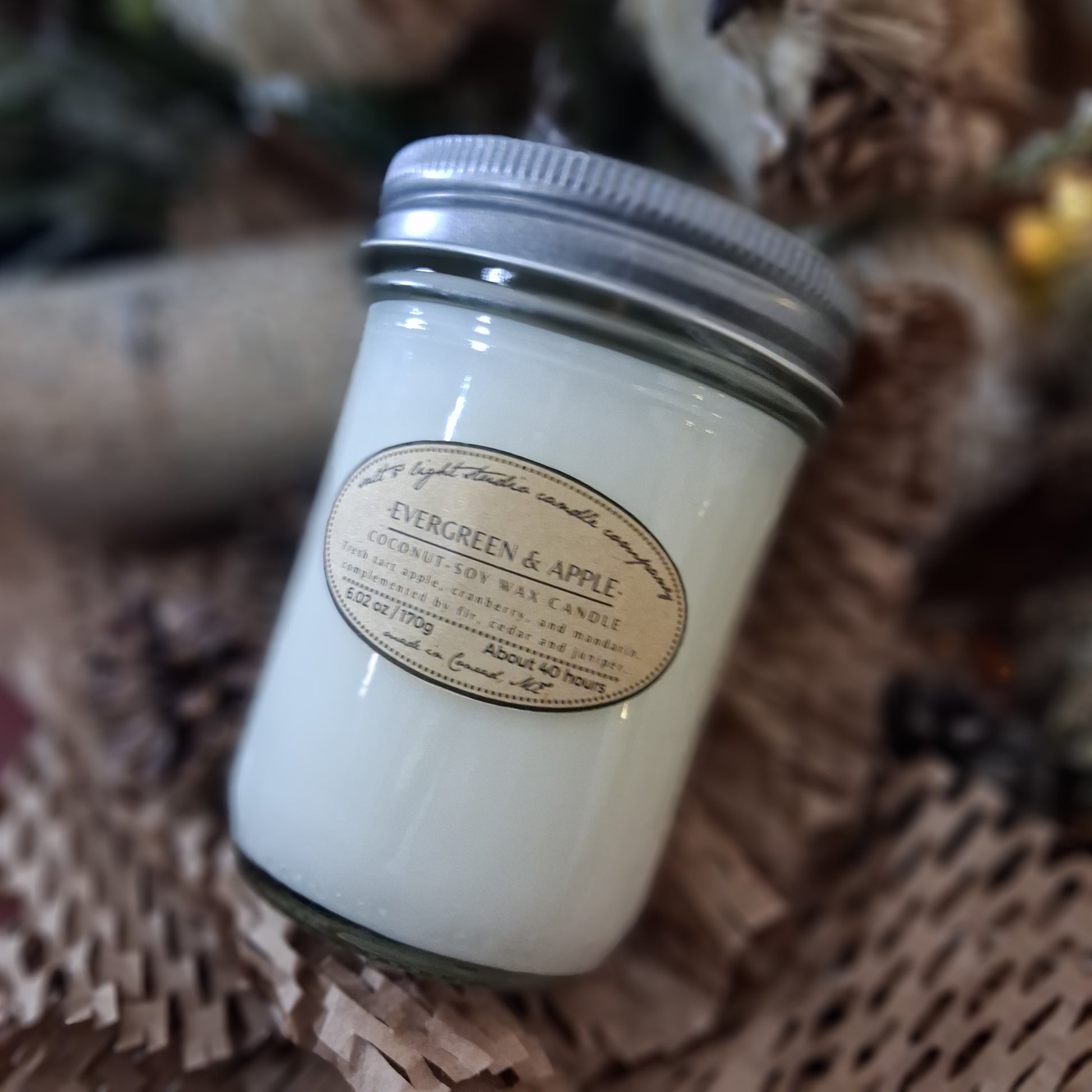 Evergreen & Apple coconut soy candle in a farmhouse mason jar on a woven paper wrapper surface