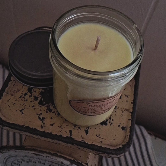 lighting a coconut soy wax candle with a match, hand poured in small batches, golden glow of candle flame